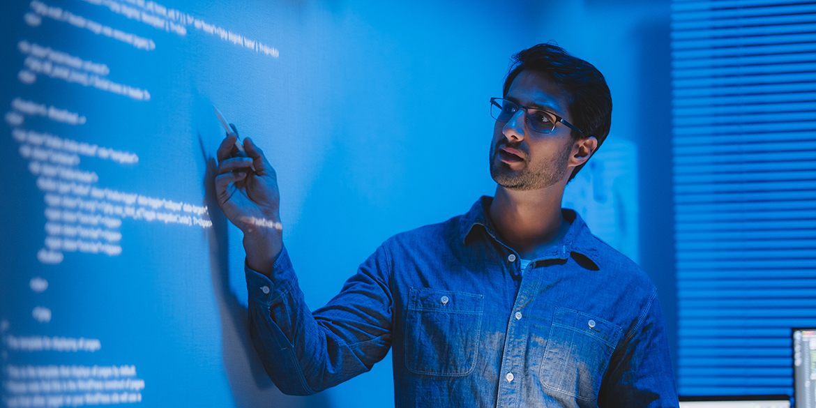 Man pointing to text projected on a wall.