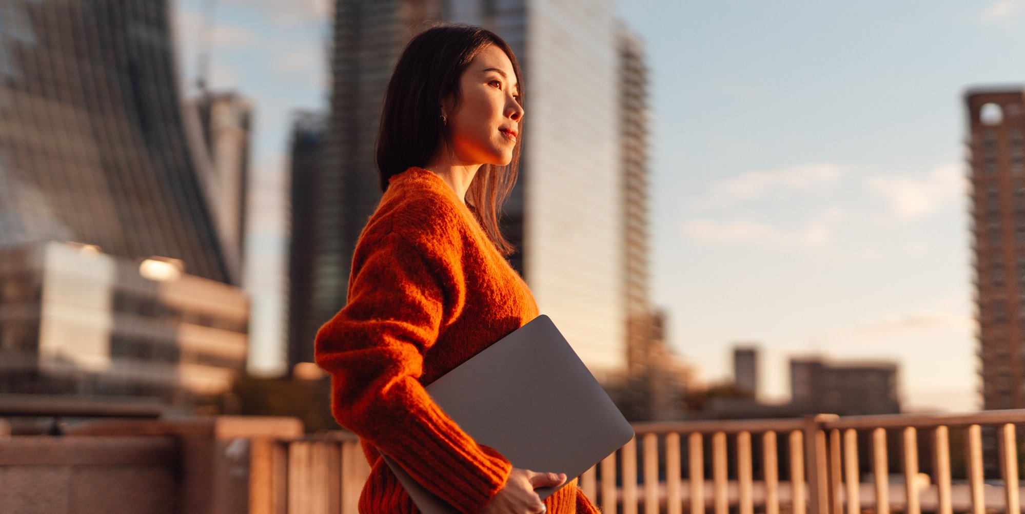 woman holding a laptop surrounded by high-rise buildings