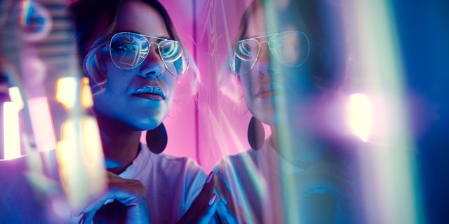 Woman with glasses looking at a digital screen.