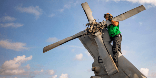 Sailor conducts maintenance on a helicopter