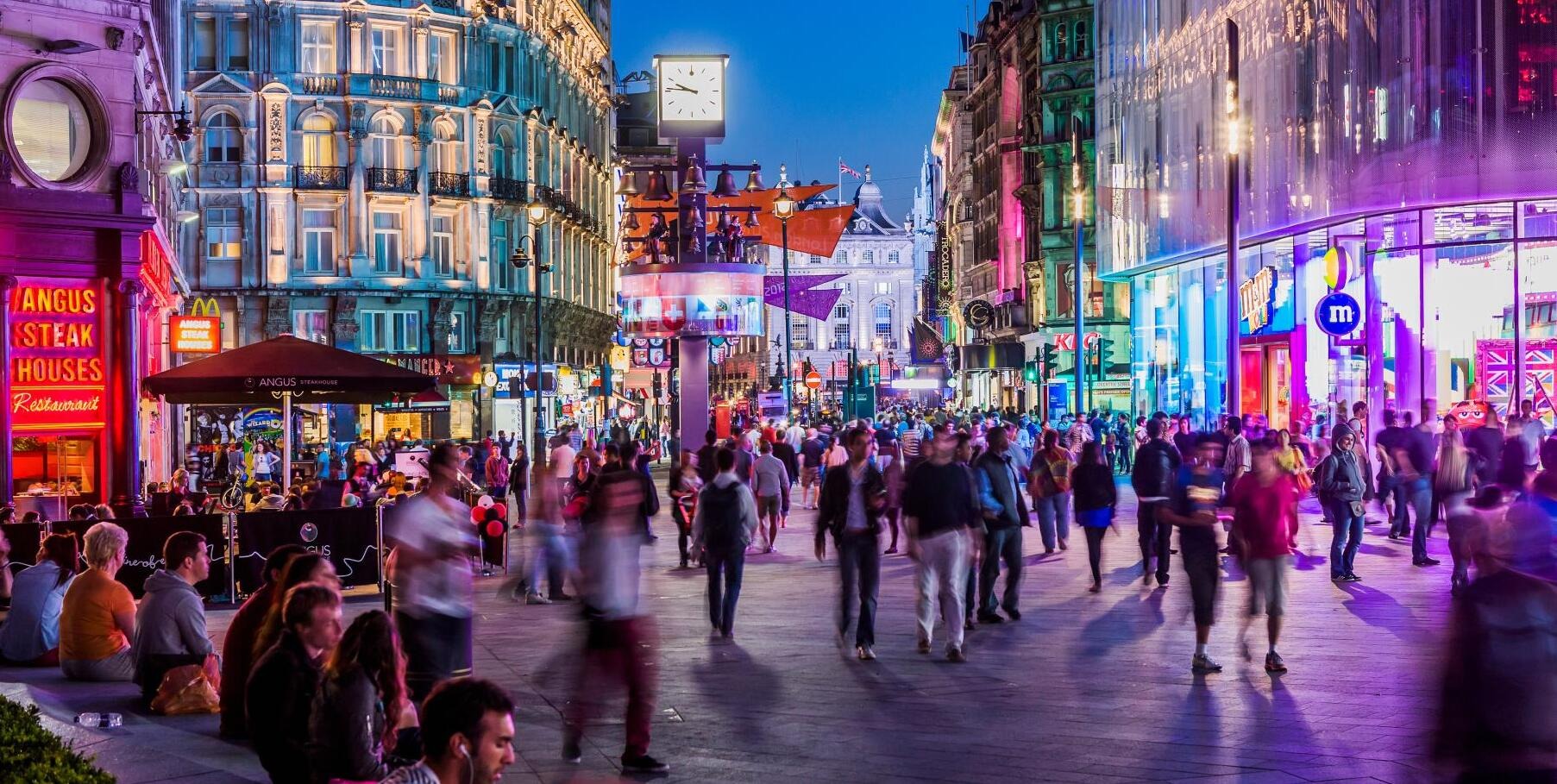 Vibrant picture of a city centre with lots of pedestrians walking in a busy, colourful city.