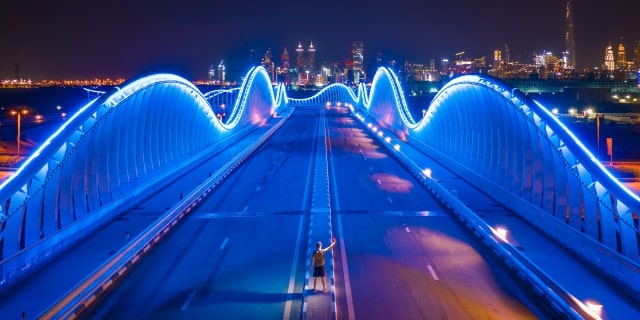 Man standing on a bridge that is lit up