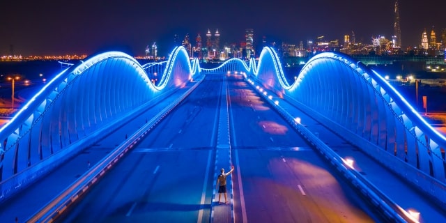 Man standing on a bridge that is lit up