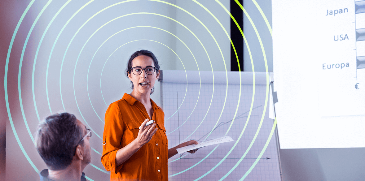 Woman talking in meeting room with flipchart behind her.