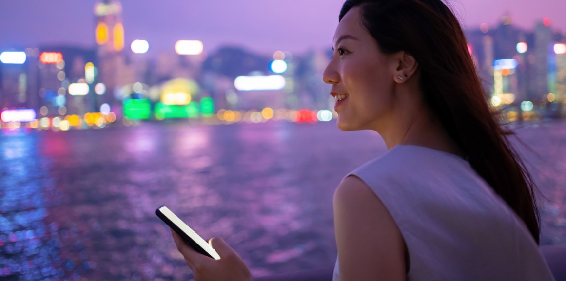 Women looking out at a river or sea at night with buildings lit in the background