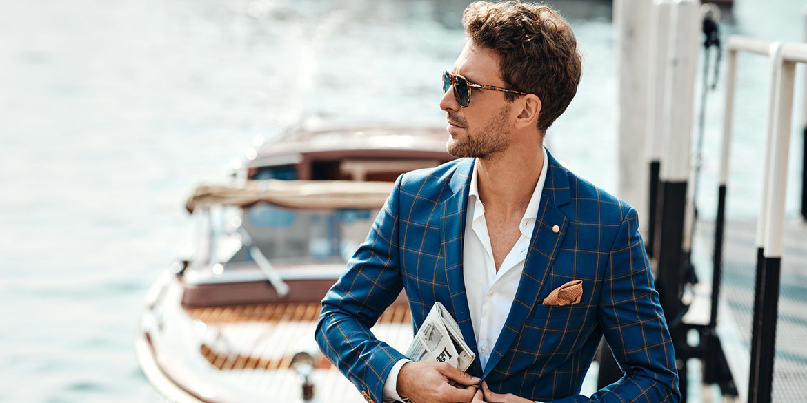 Smart man doing up his jacket in front of yacht