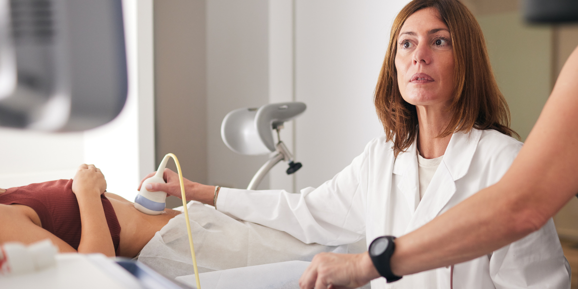 Woman performing ultrasound on another woman's stomach.